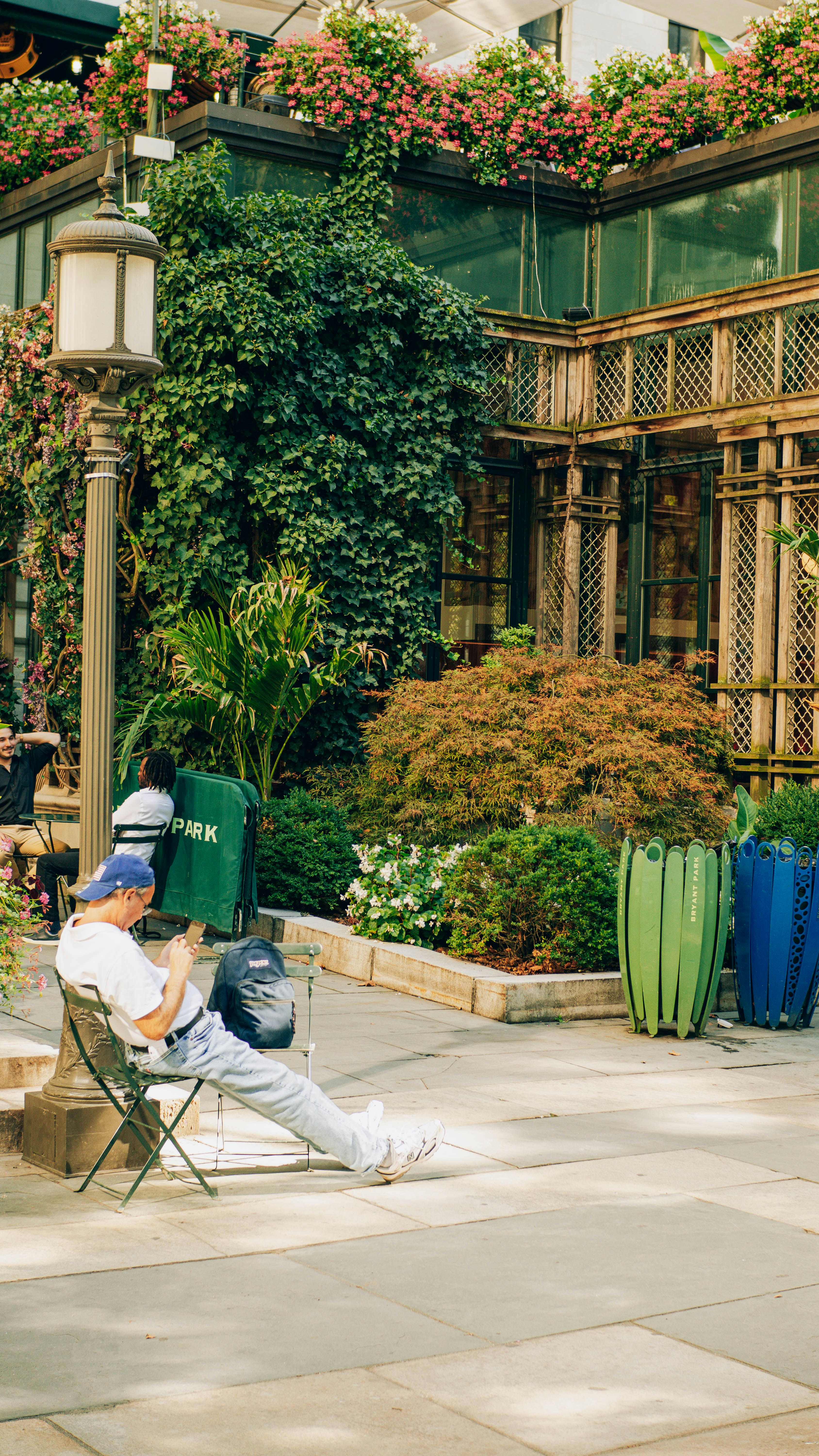 Man sitting on chair in lush green garden setting.