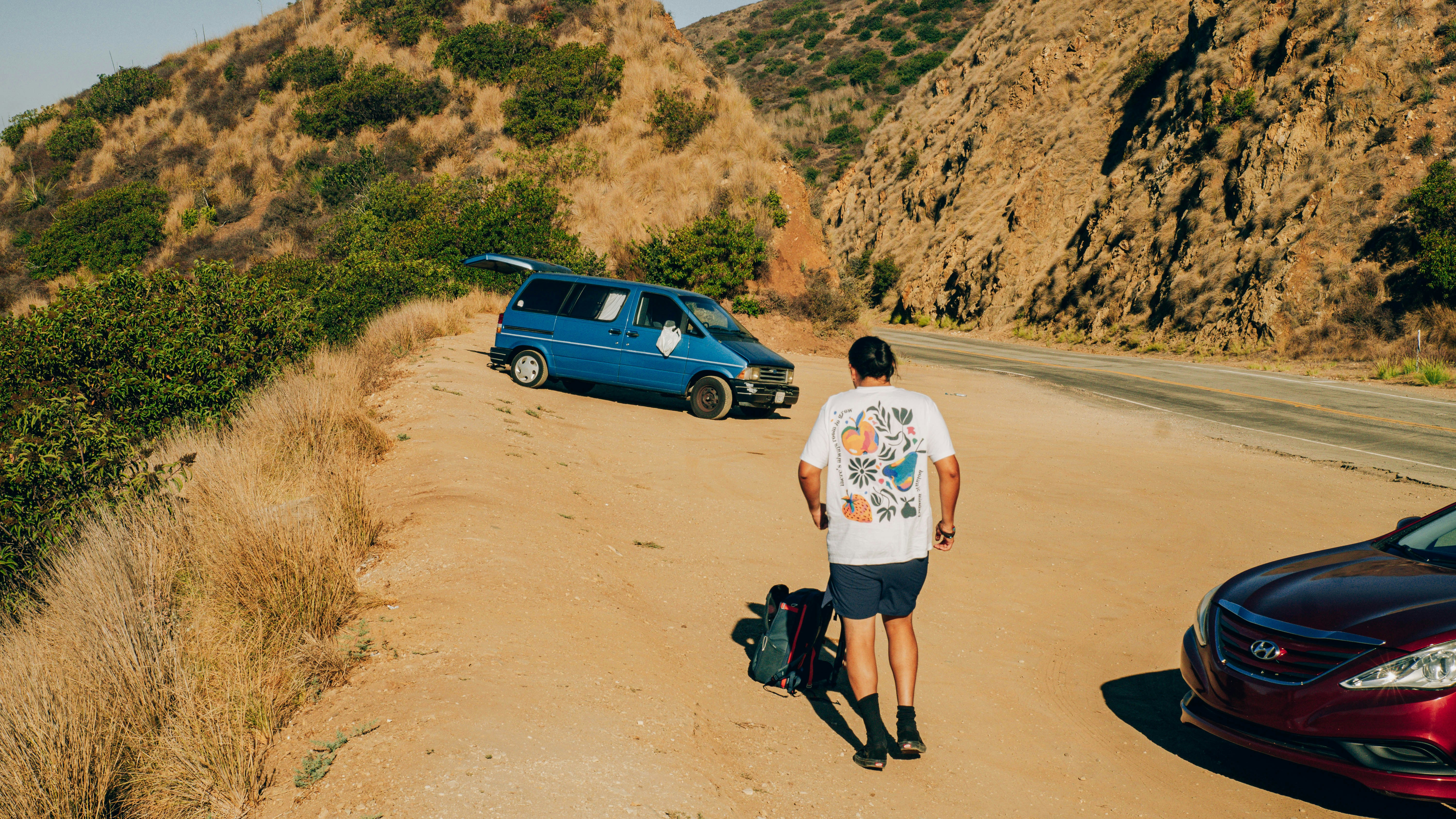 Man walking towards blue van on a dirt road