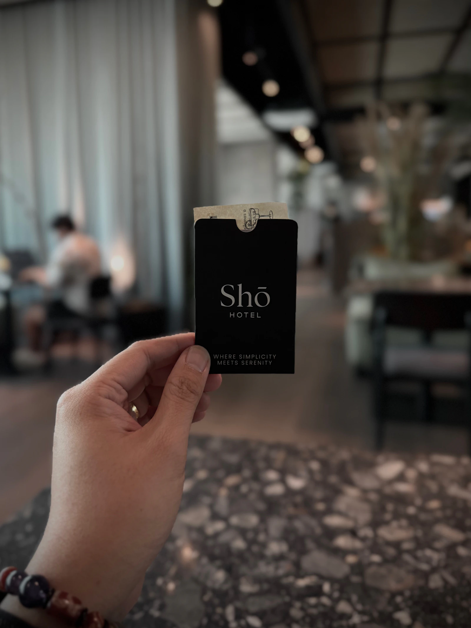 A hand holding a hotel key card up to a door lock
