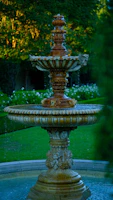 Ornate tiered fountain with water flowing in a garden.