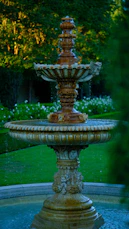 Ornate tiered fountain with water flowing in a garden.