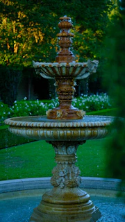 Ornate tiered fountain with water flowing in a garden.