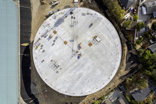 Large circular structure under construction with cranes.