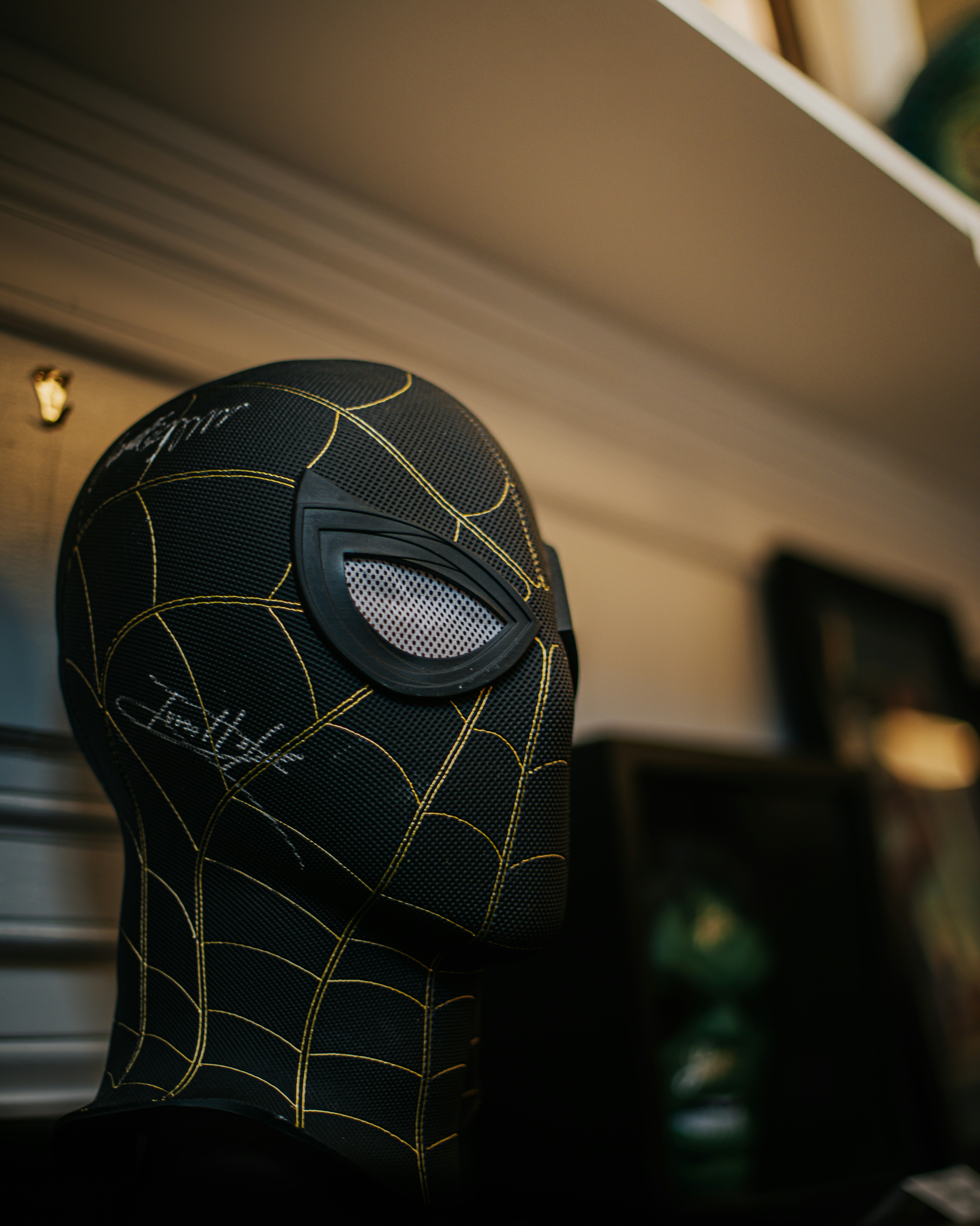Topeng spider-man hitam dengan detail jaring emas