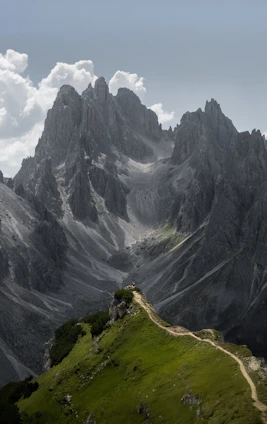 A winding mountain path leads to jagged peaks.