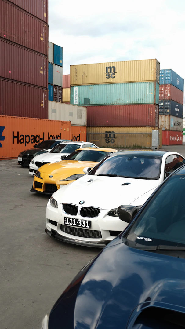 Several cars parked near shipping containers