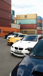 Several cars parked near shipping containers
