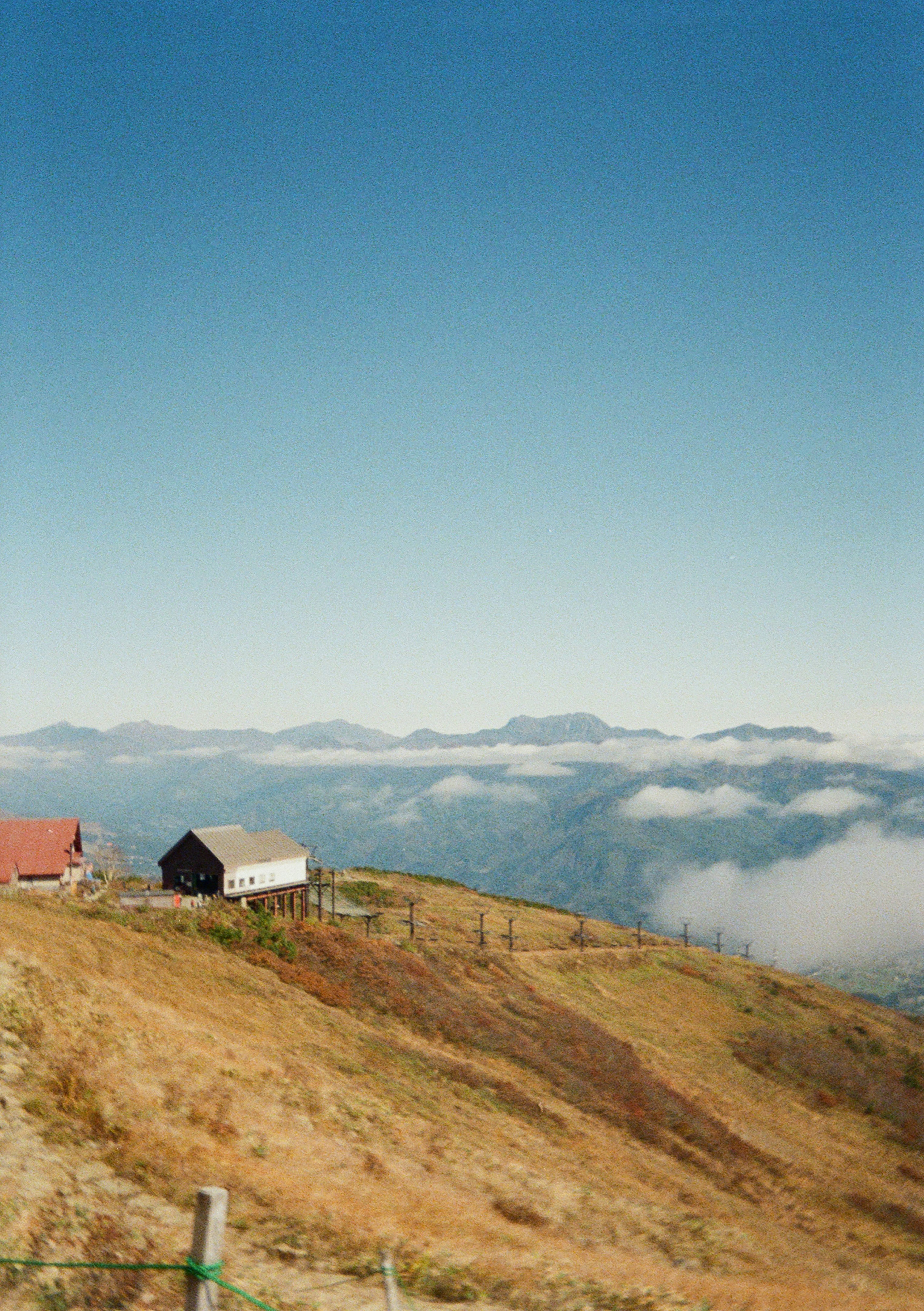 Pequeñas casas en la ladera de una montaña cubierta de hierba por encima de las nubes.