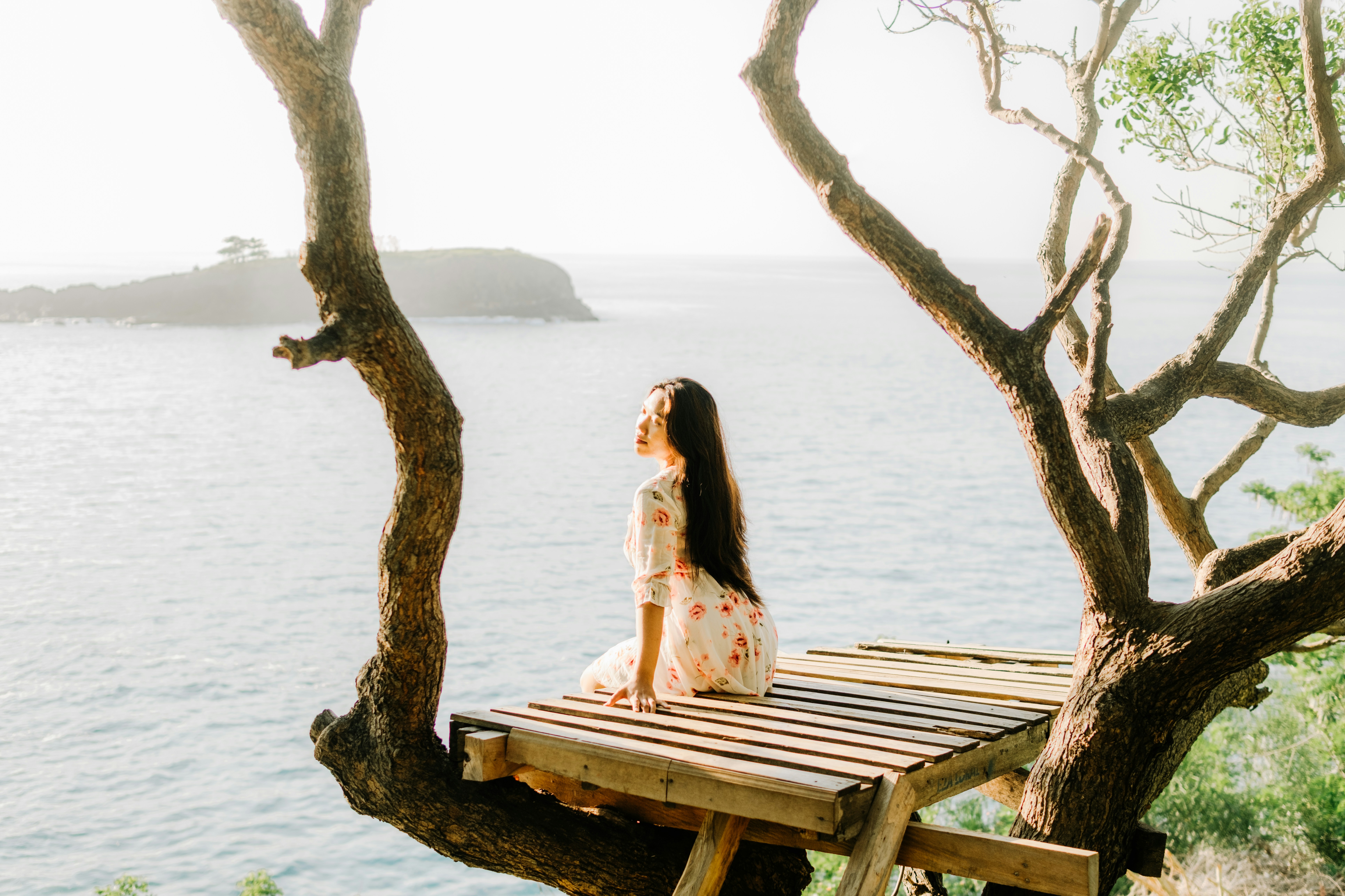 A happy person sitting peacefully alone in a cozy cafe, smiling and looking out a window while holding a warm mug, representing the joy and independence of being single.