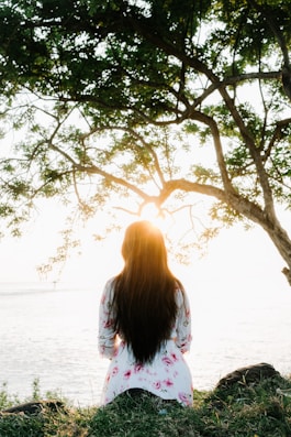 Woman sitting under a tree at sunset