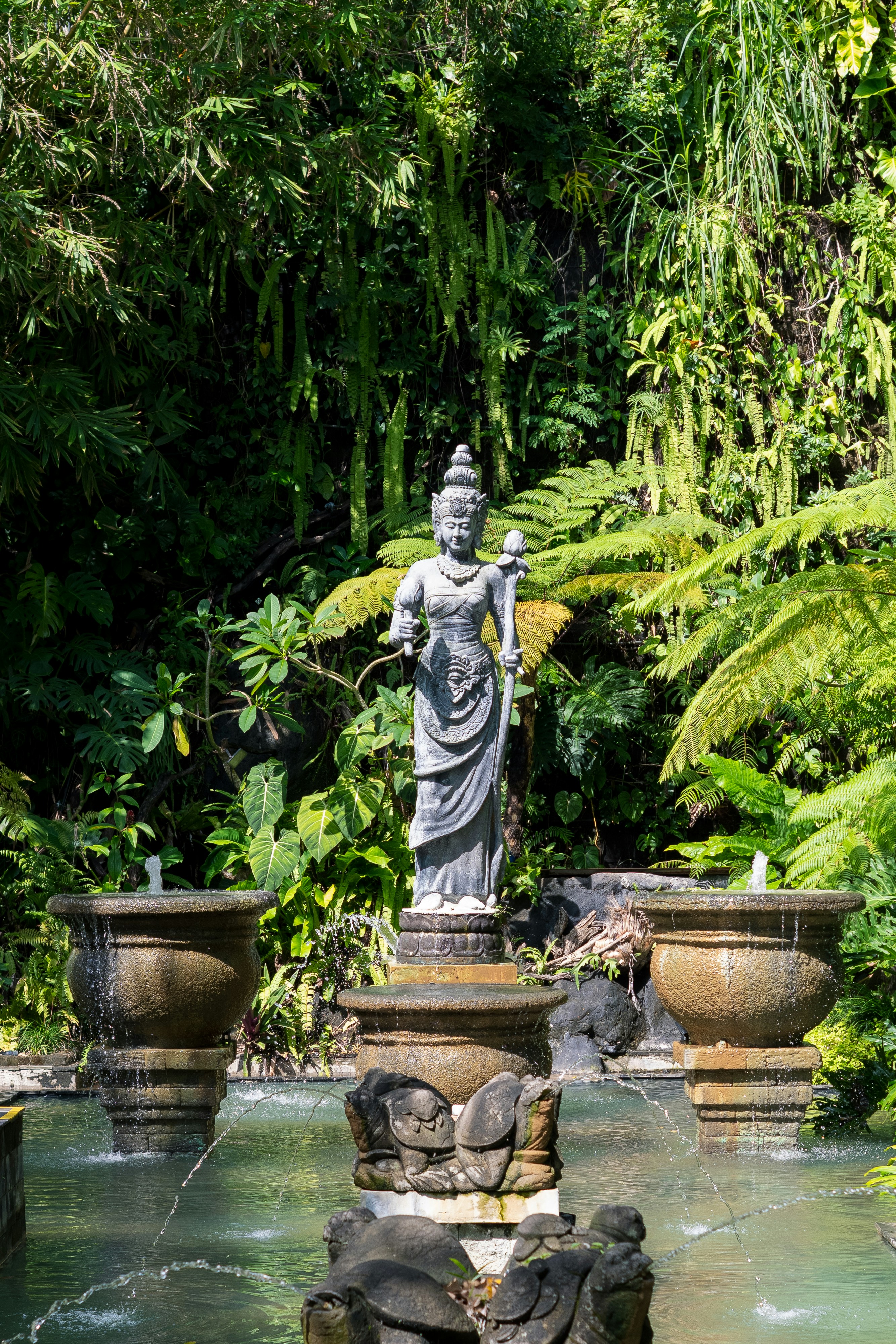 Stone statue in lush garden with fountains