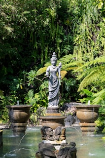 Stone statue in lush garden with fountains