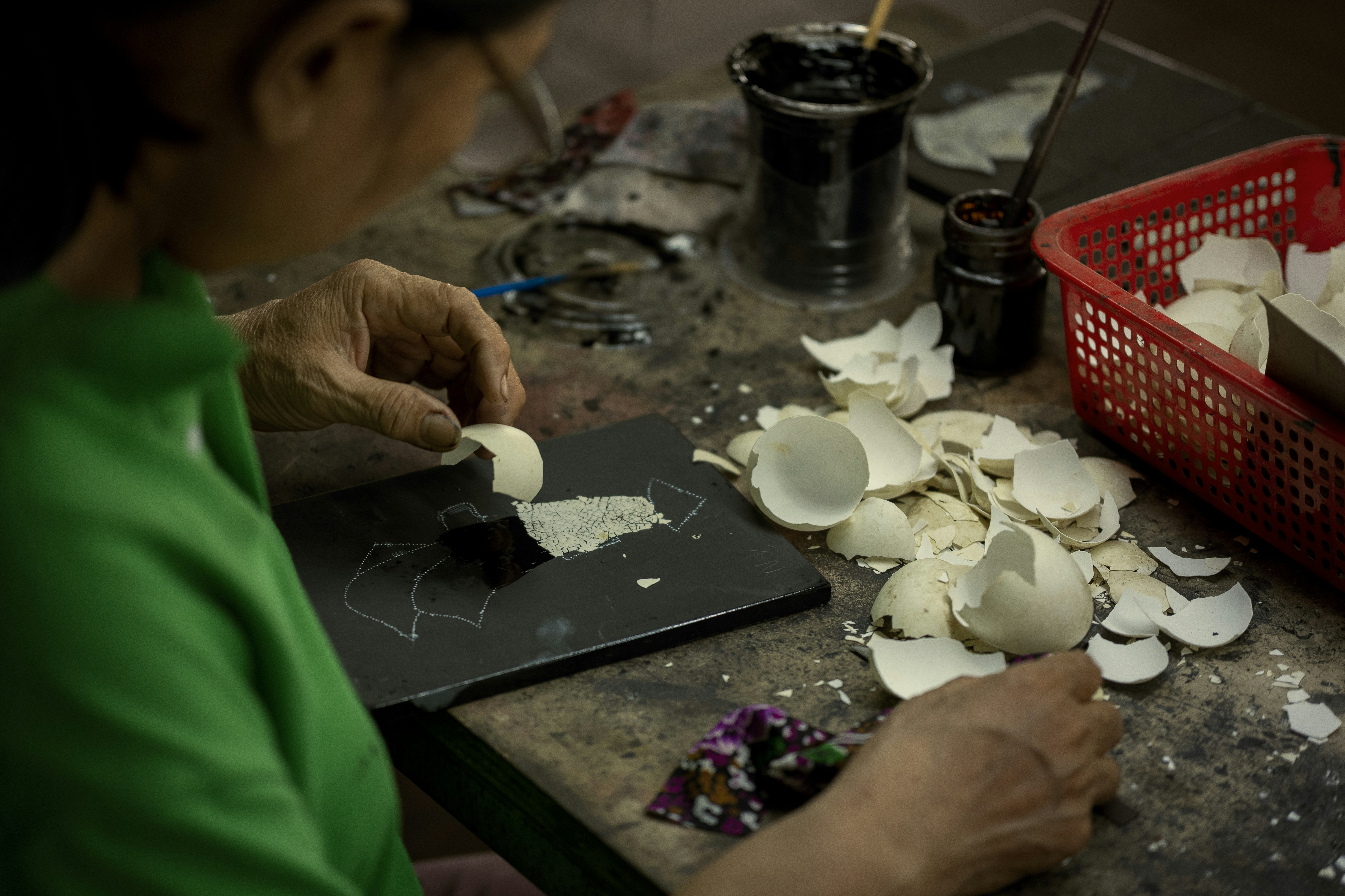 Person crafting with eggshells and small flowers.