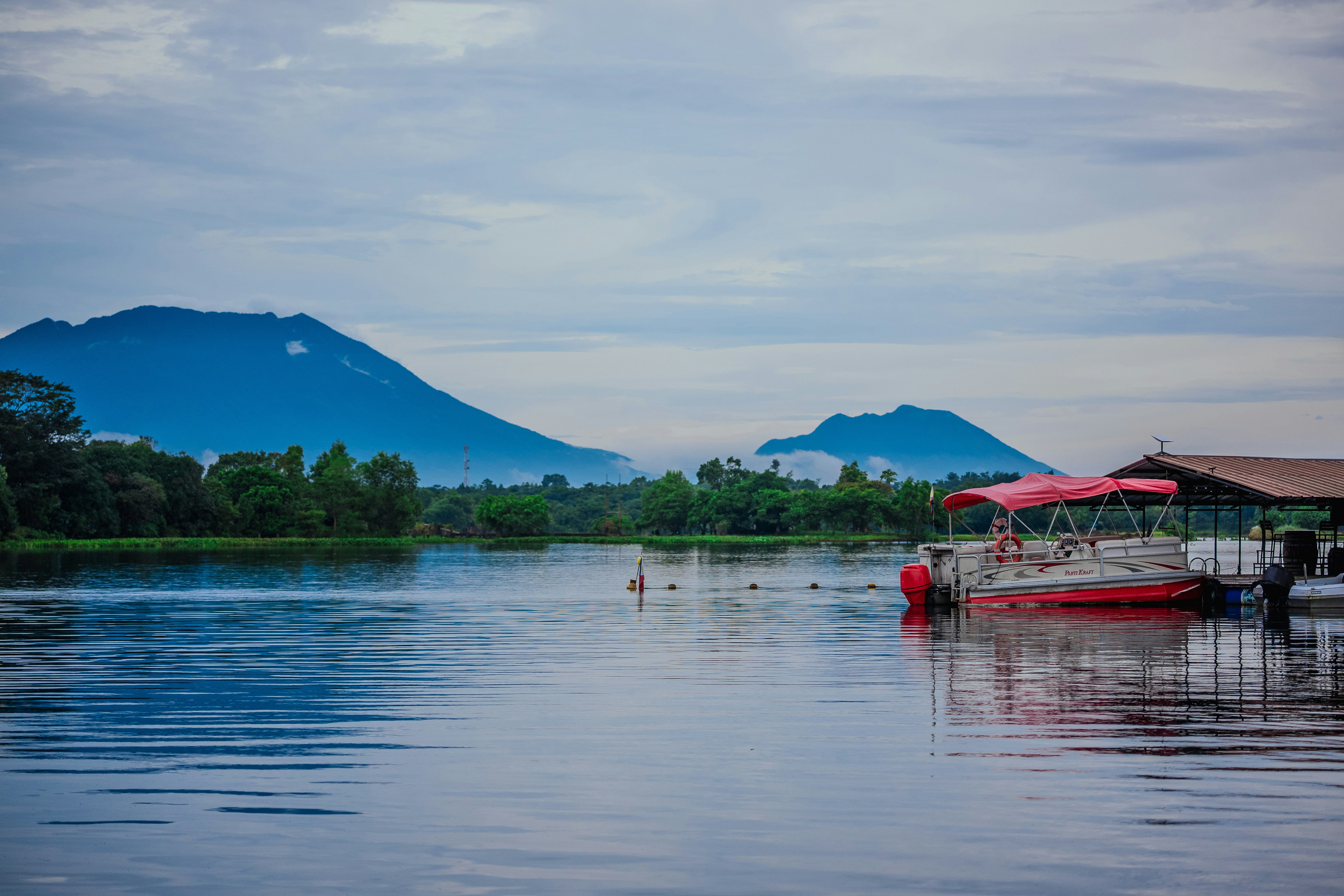 Boat docked on a calm lake with mountains in background