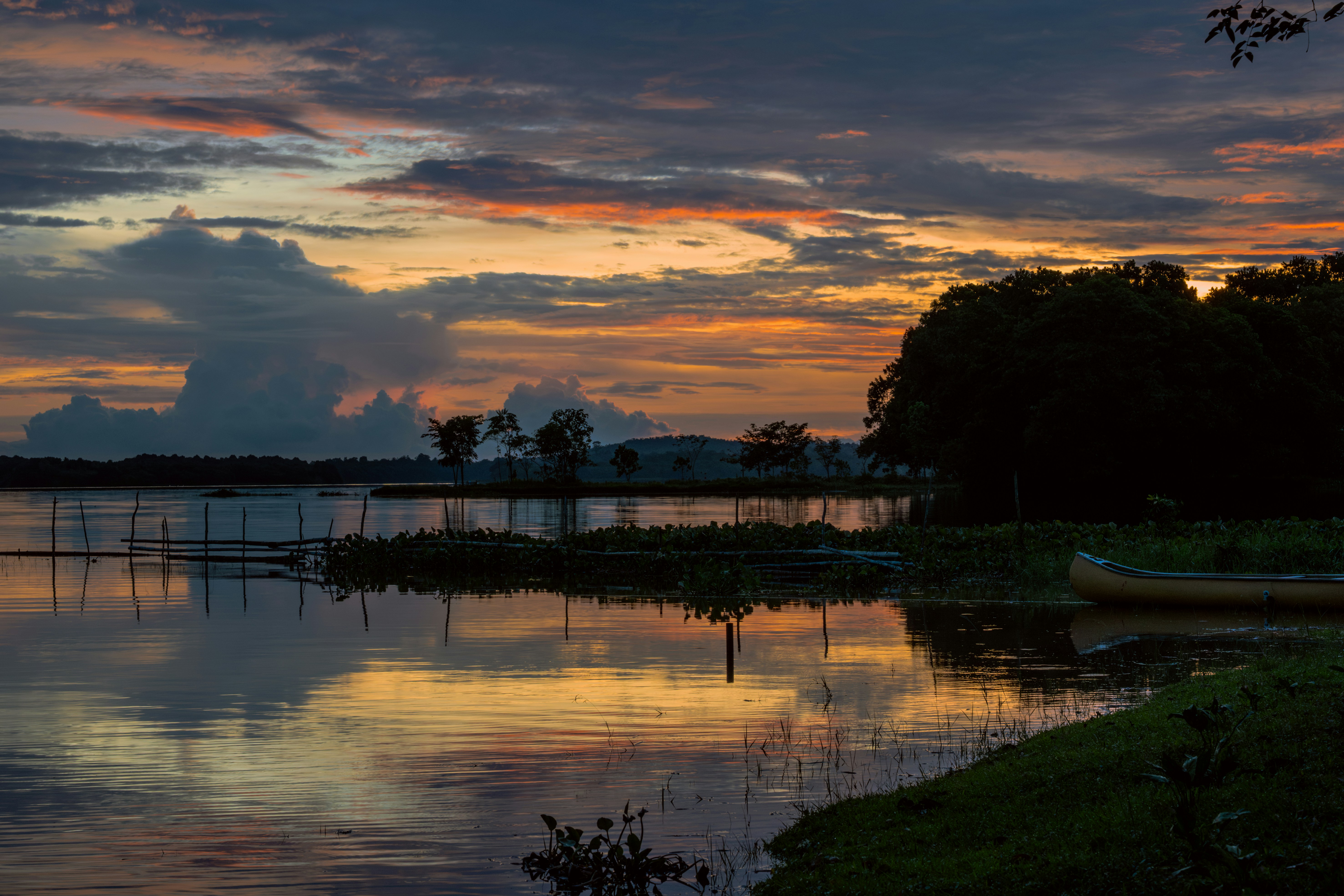 Colorful sunset over a tranquil lake with trees.
