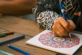 Person coloring a mandala with markers on paper
