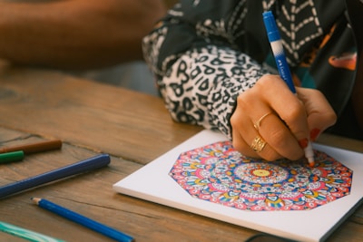 Person coloring a mandala with markers on paper
