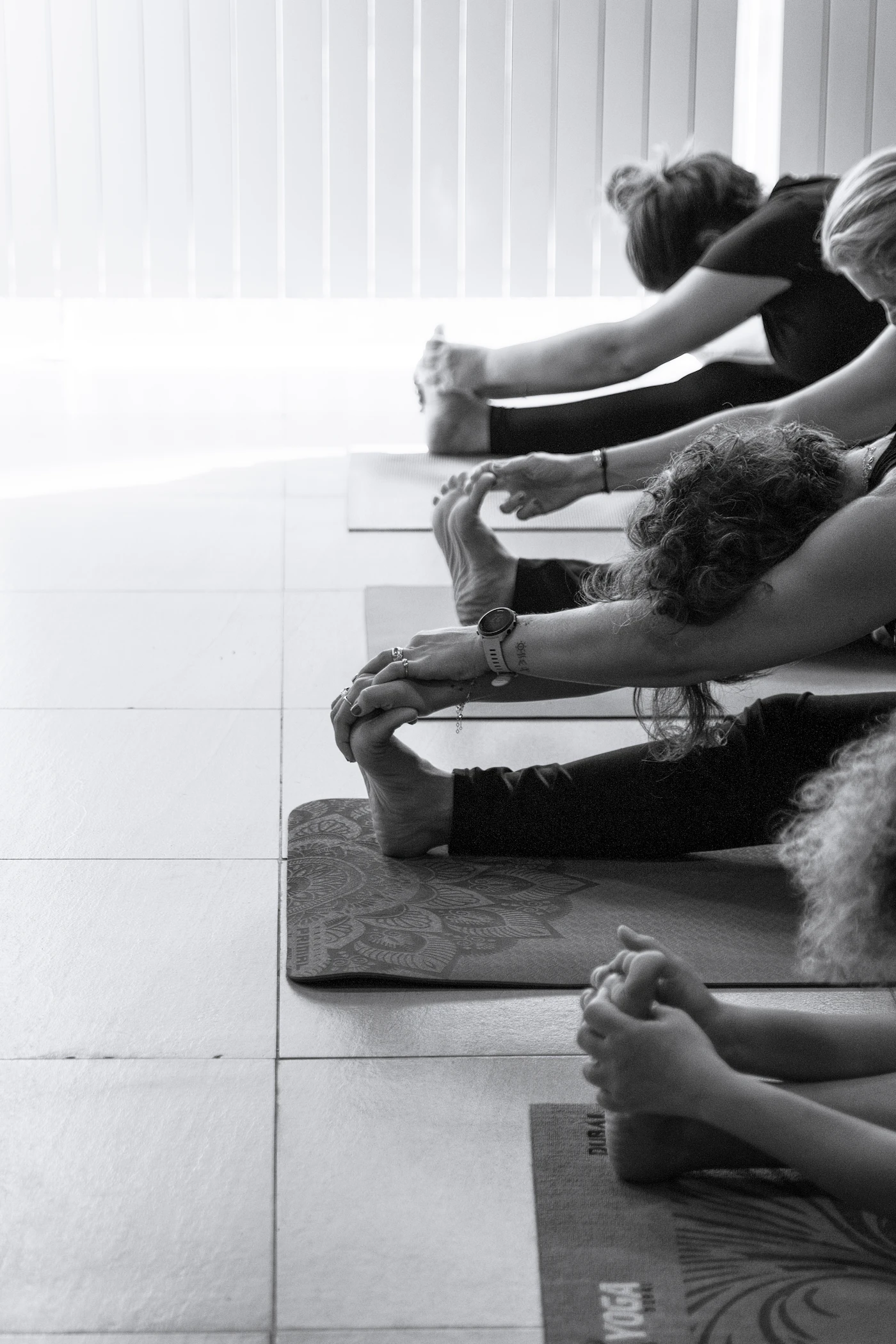 Members stretching on yoga mats during a class in a bright studio
