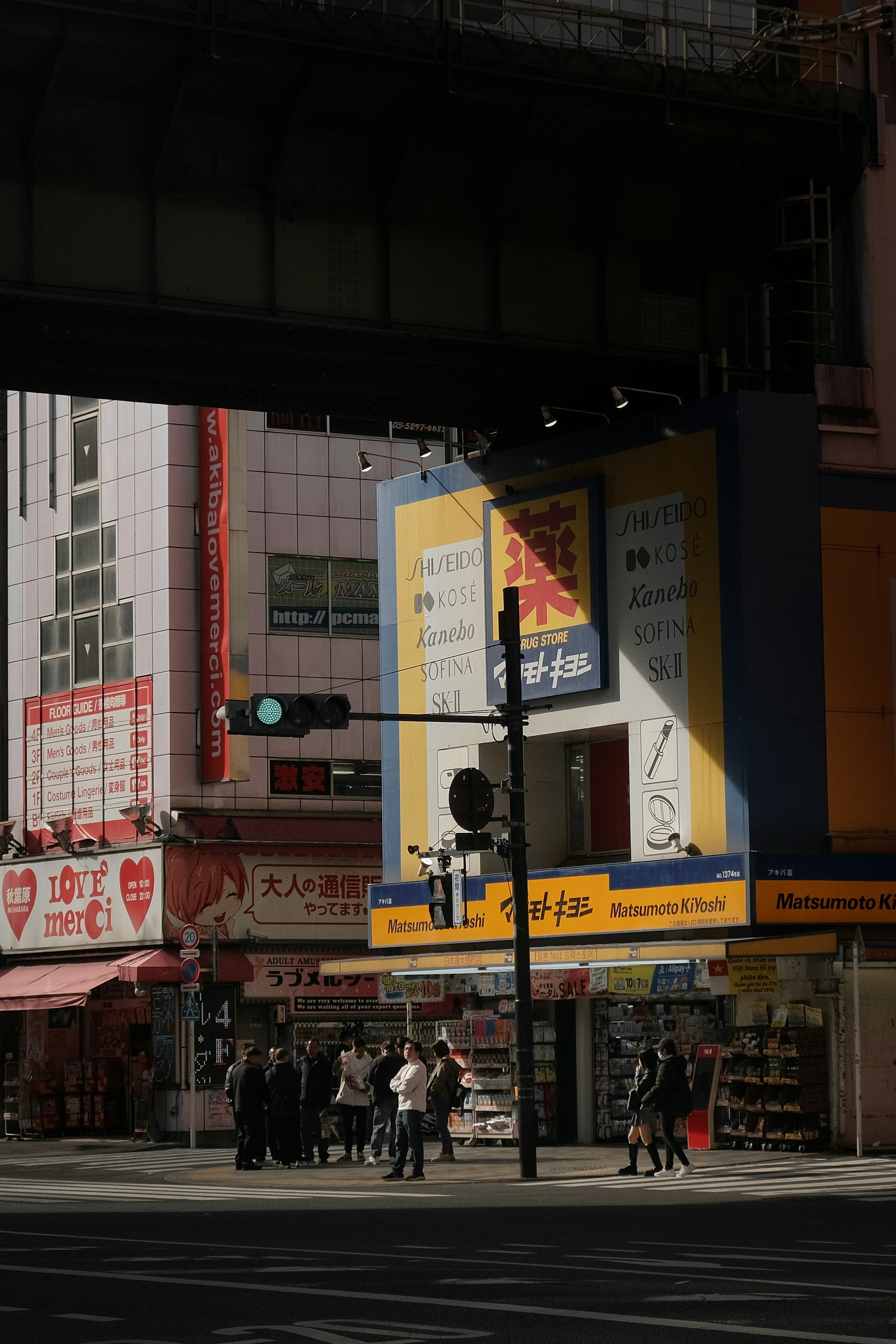 People walk on a street in front of shops.