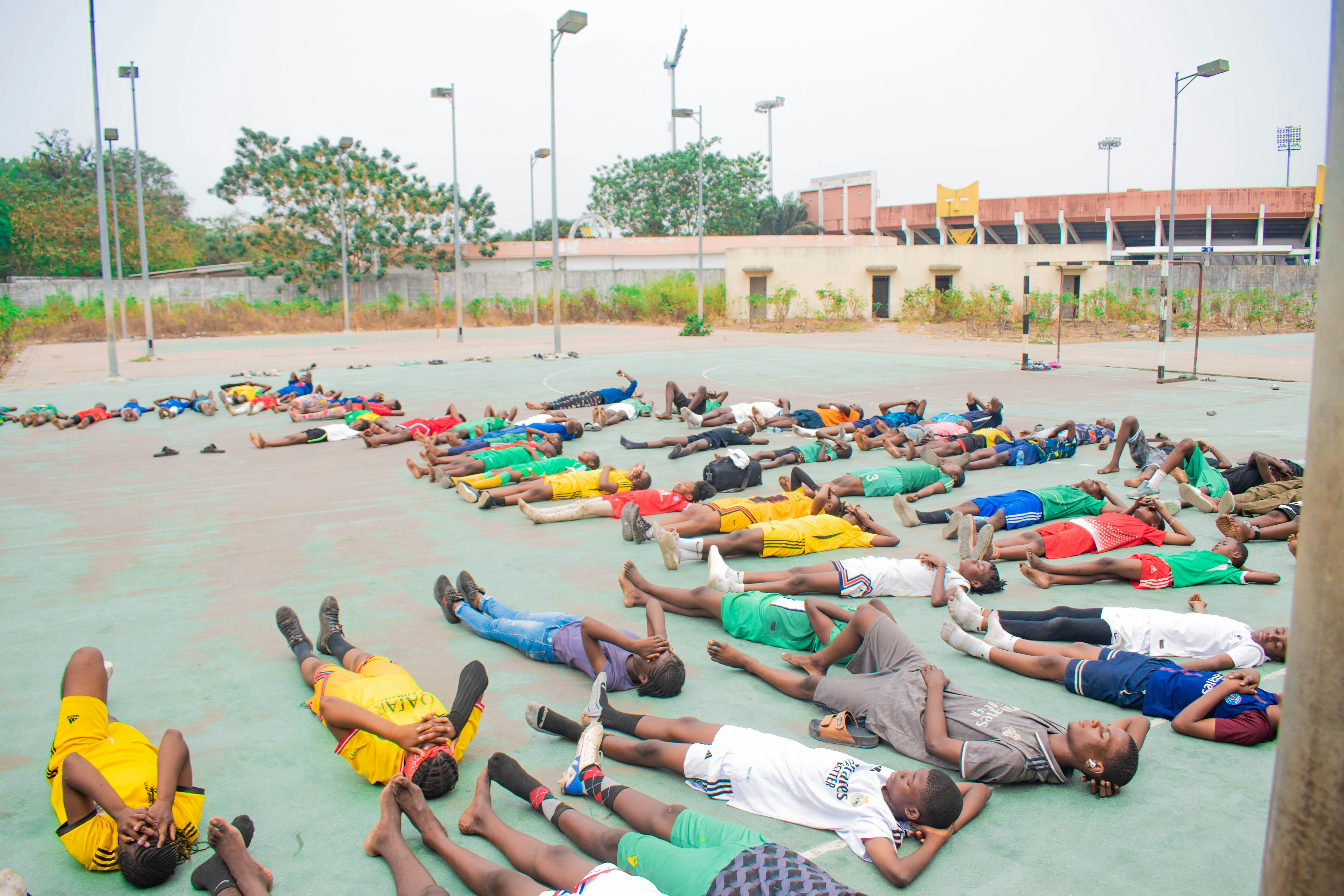 Group of people lying on the ground outside.