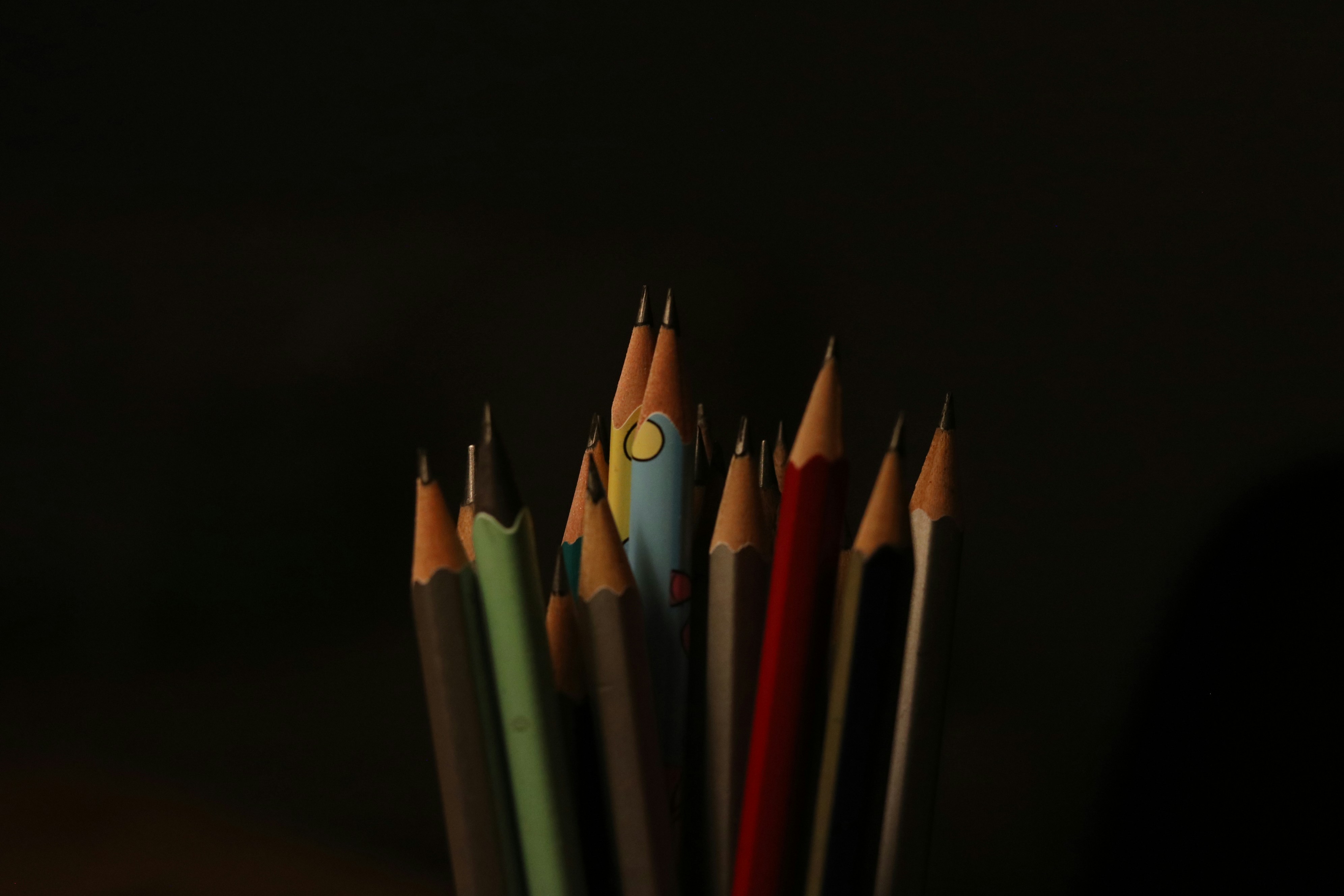 A collection of sharpened pencils against a dark background.