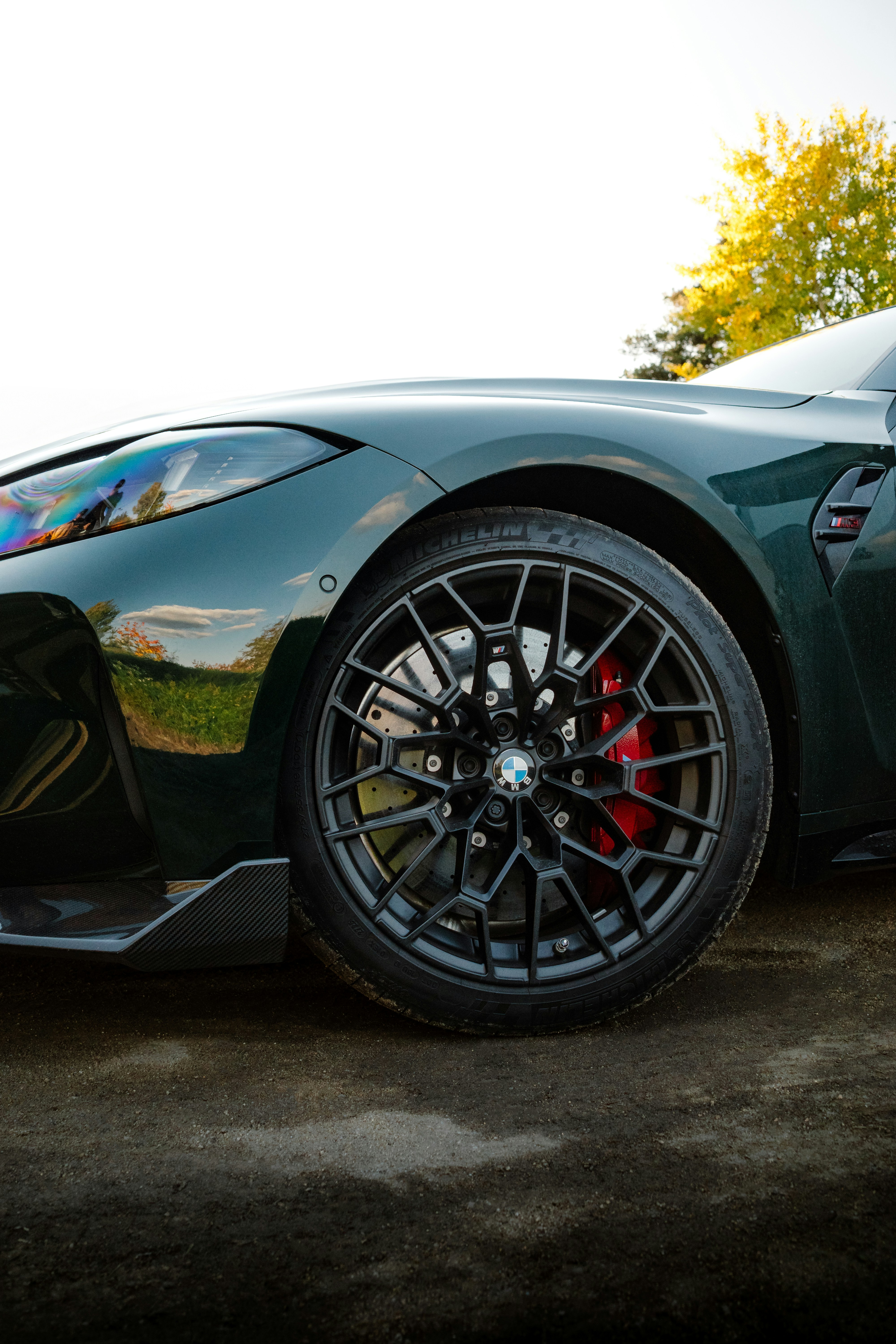 Close-up of a dark green car wheel and fender.