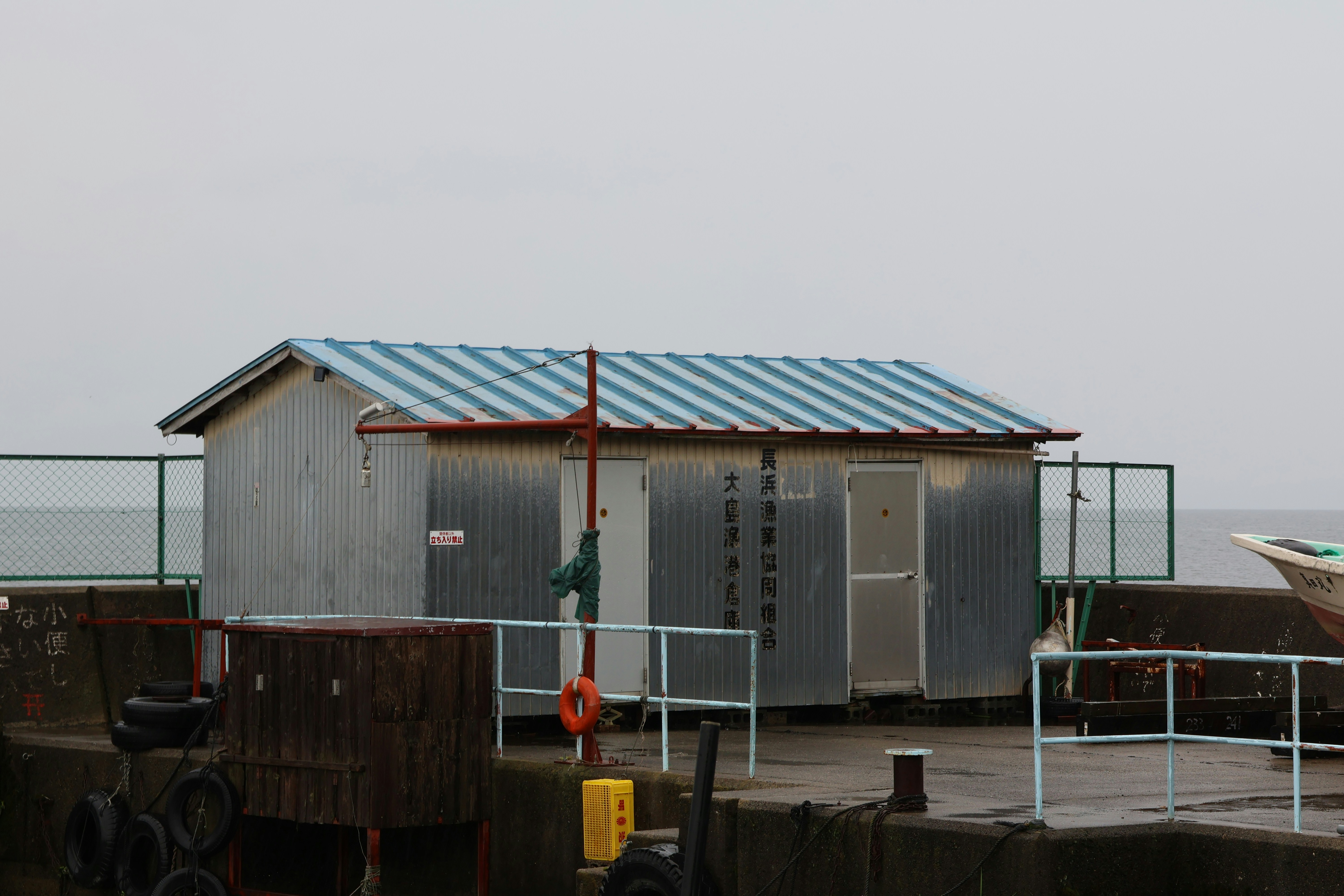 Small metal building with striped roof on pier