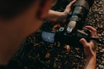 Hands holding a professional camera on the ground
