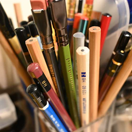 Assortment of pencils and art supplies in a container