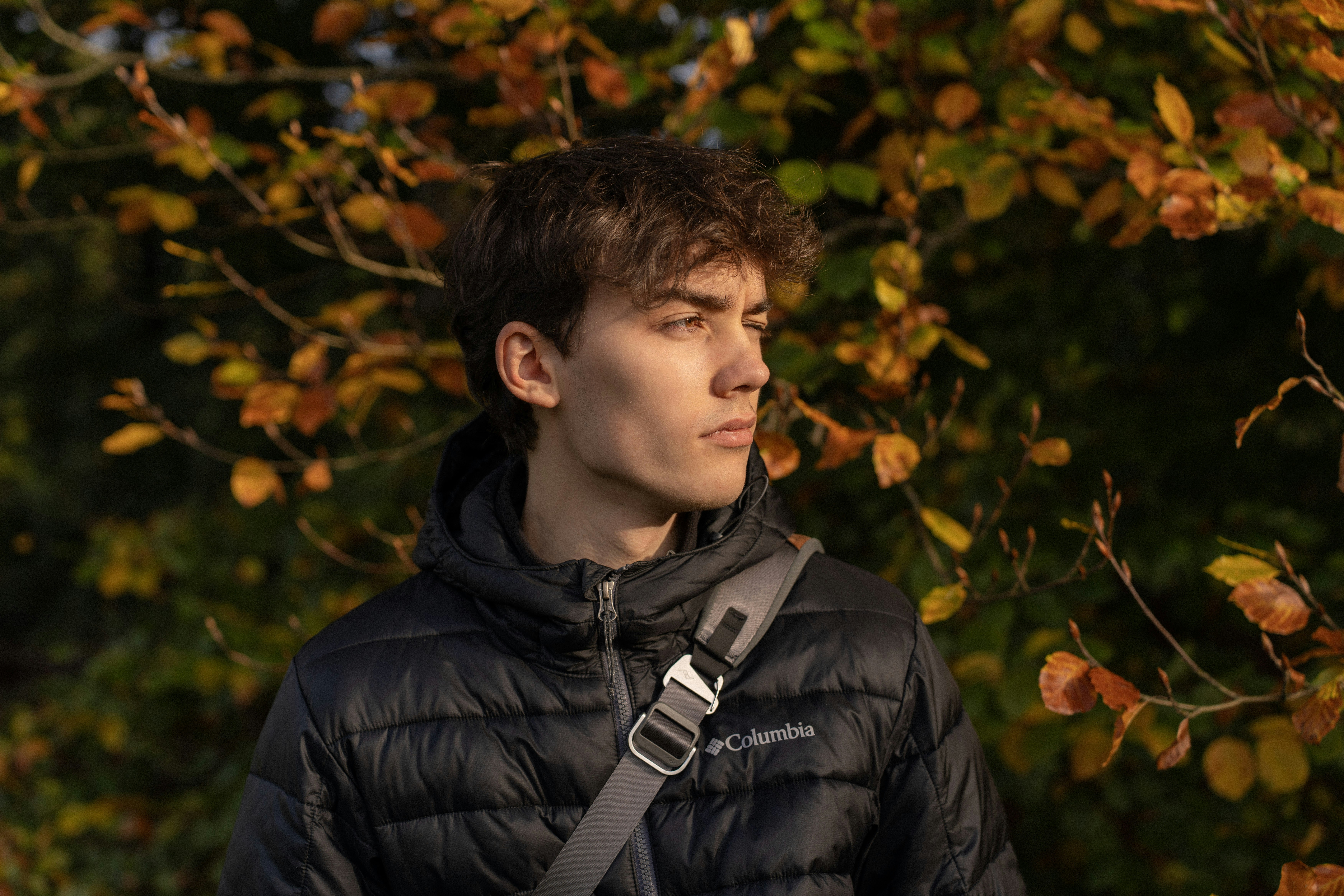 Young man in a puffer jacket with autumn leaves