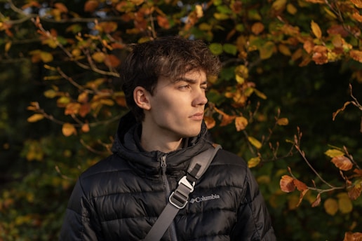 Young man in a puffer jacket with autumn leaves