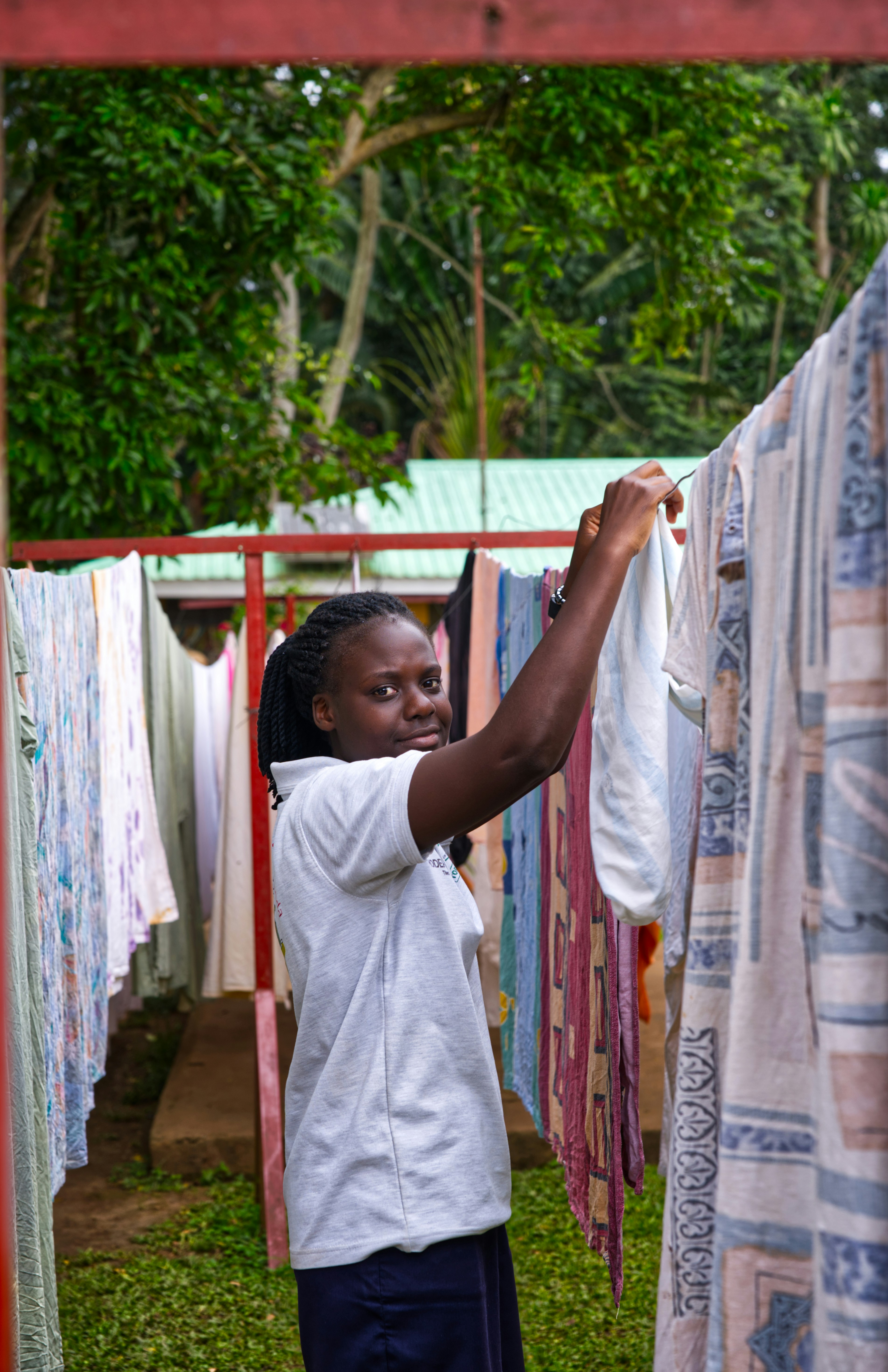 Young woman hangs laundry on a clothesline outdoors.