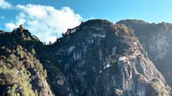 Steep, forested mountains under a blue sky.