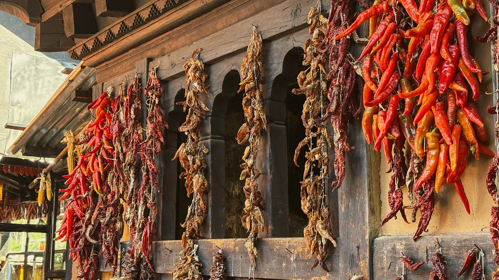 Strings of red chillies drying on the carved wooden front of a traditional house in Thimphu, Bhutan
