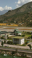 Airport buildings nestled by a river and mountains.
