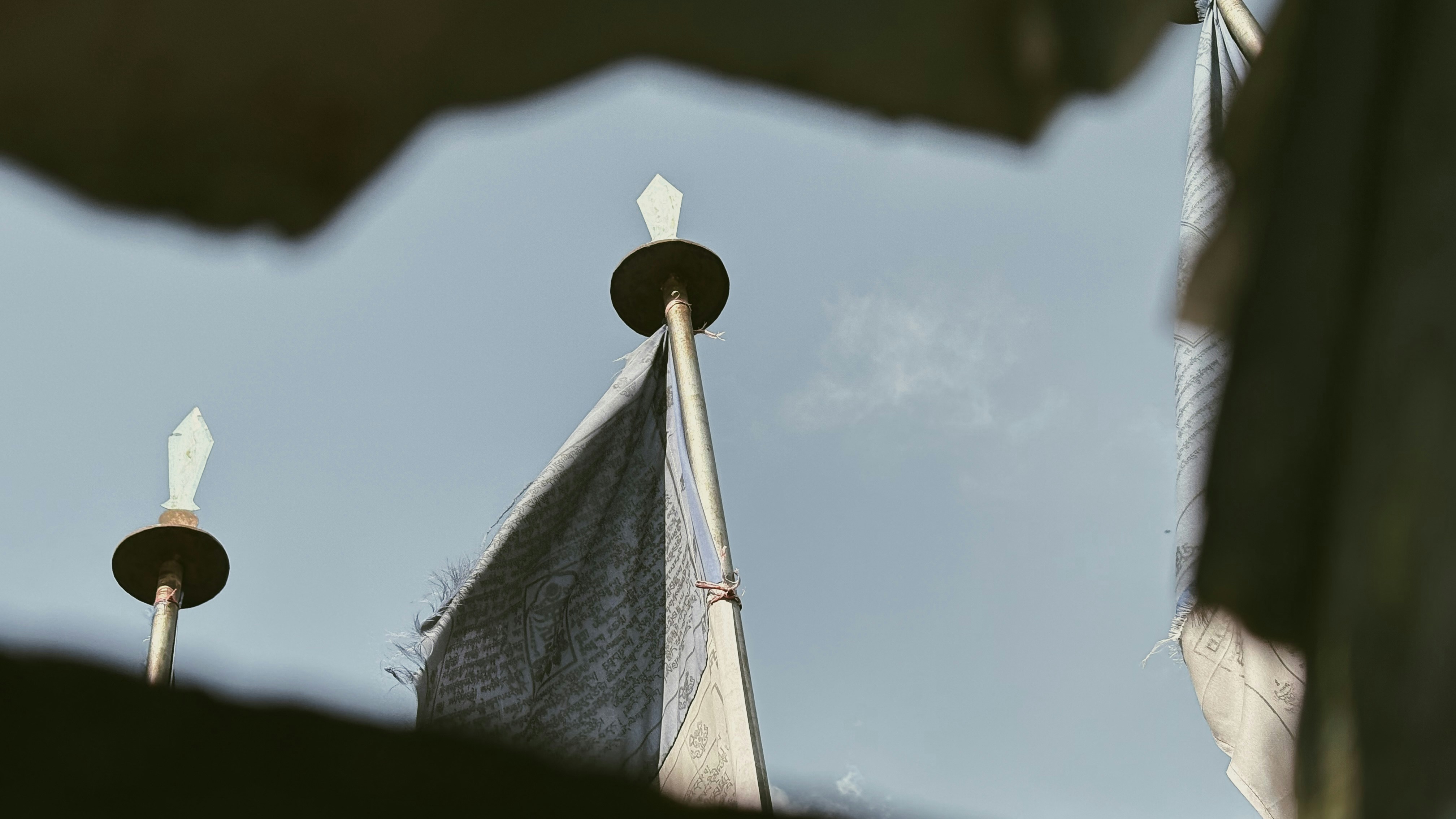 Tattered flags fly against a clear blue sky.