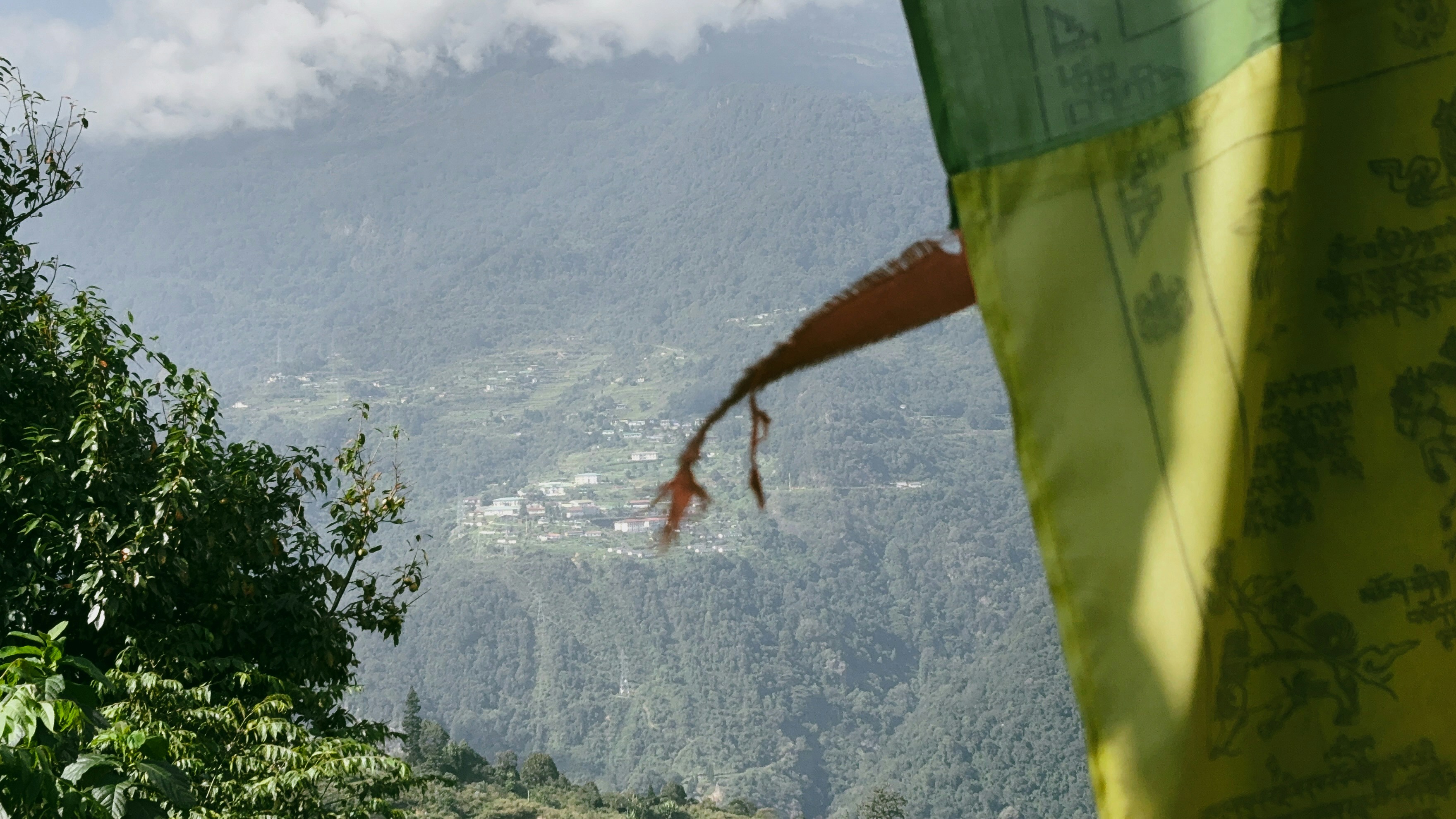 Colorful Bhutanese prayer flags flutter gently against the backdrop of Thimphu’s lush mountain slopes, blending spirituality and natural beauty in a tranquil Himalayan setting.