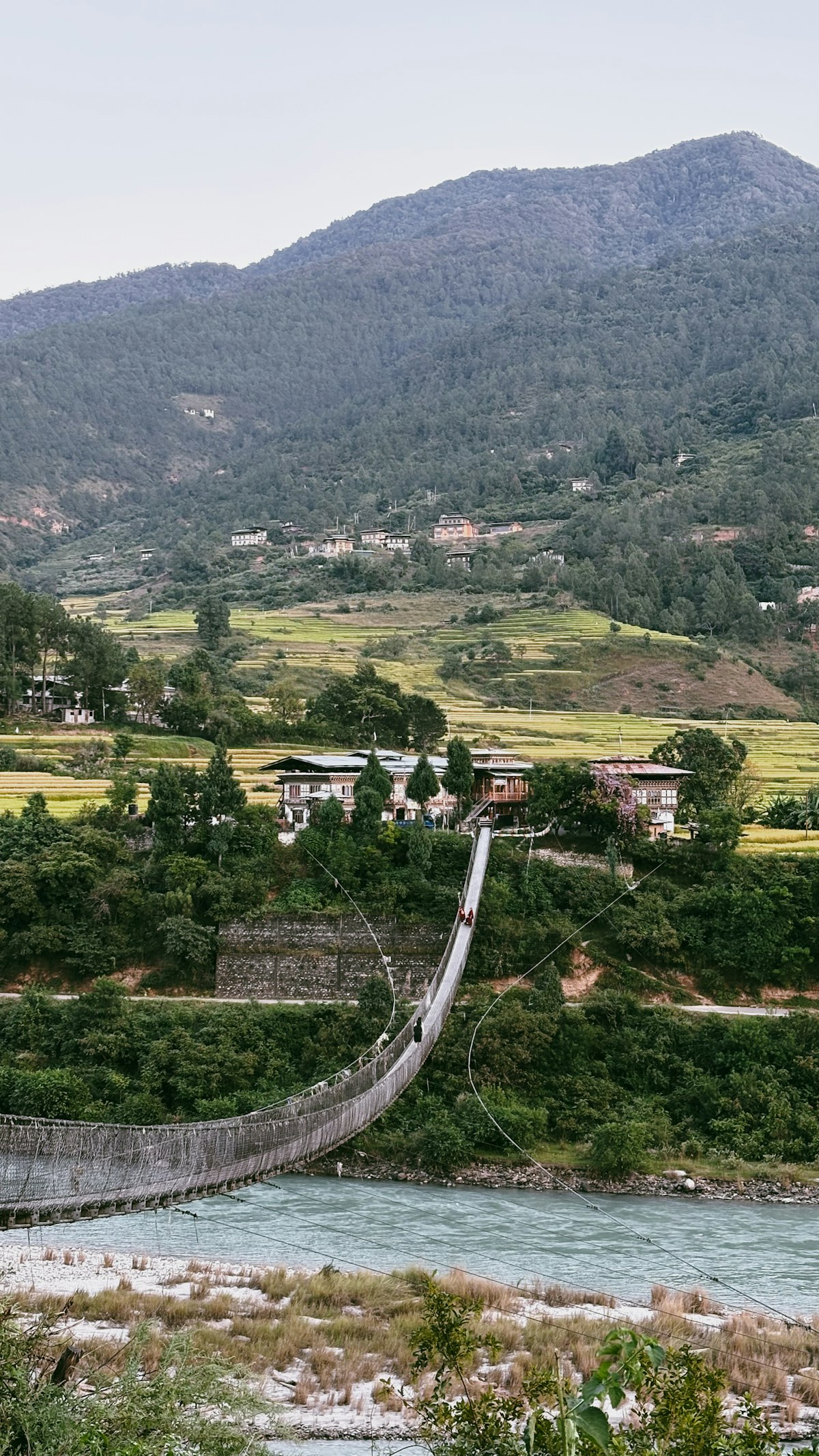 Suspension bridge over a Himalayan river with green hillsides