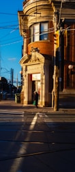 Person walks past a brick bank building at sunset.