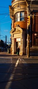 Person walks past a brick bank building at sunset.