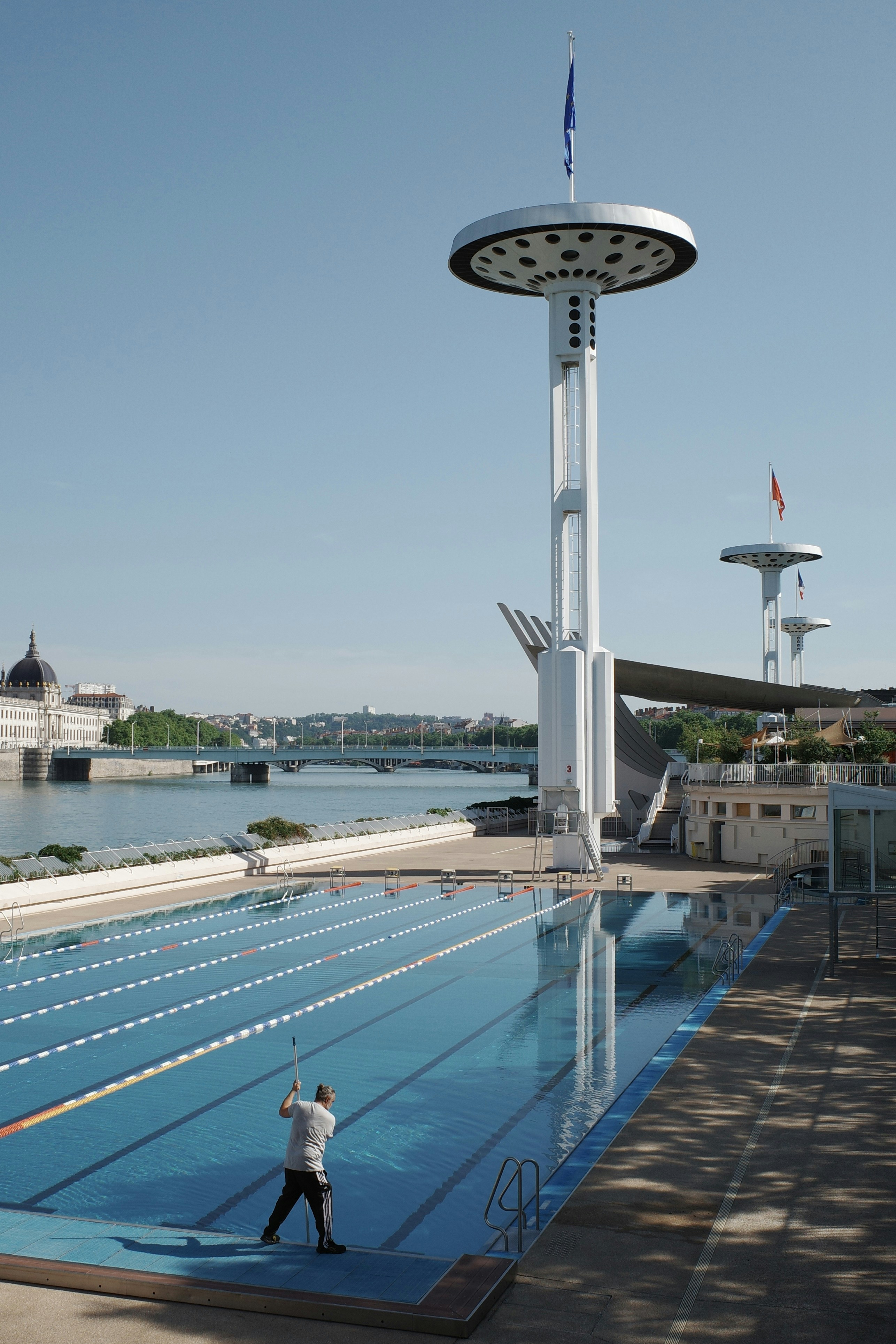 Man cleaning an empty swimming pool near a river.
