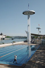 Man cleaning an empty swimming pool near a river.