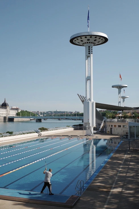 Man cleaning an empty swimming pool near a river.