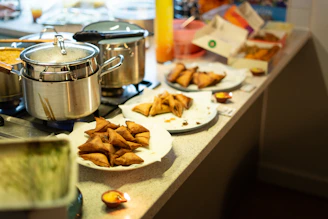 Samosas and food served on plates on a counter.