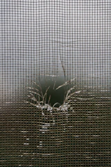 A torn window screen with a hole in it