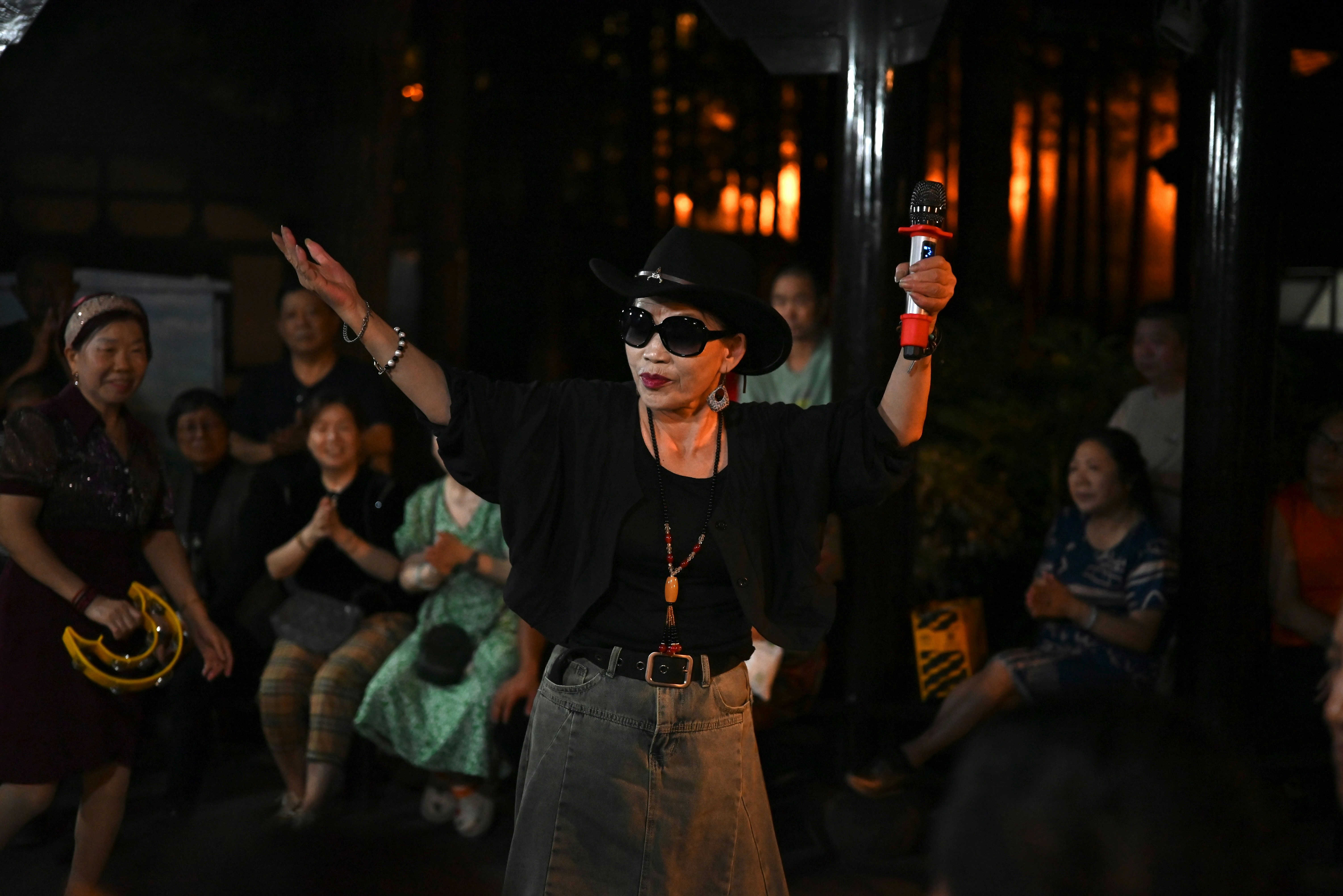 Woman in hat and sunglasses singing into microphone