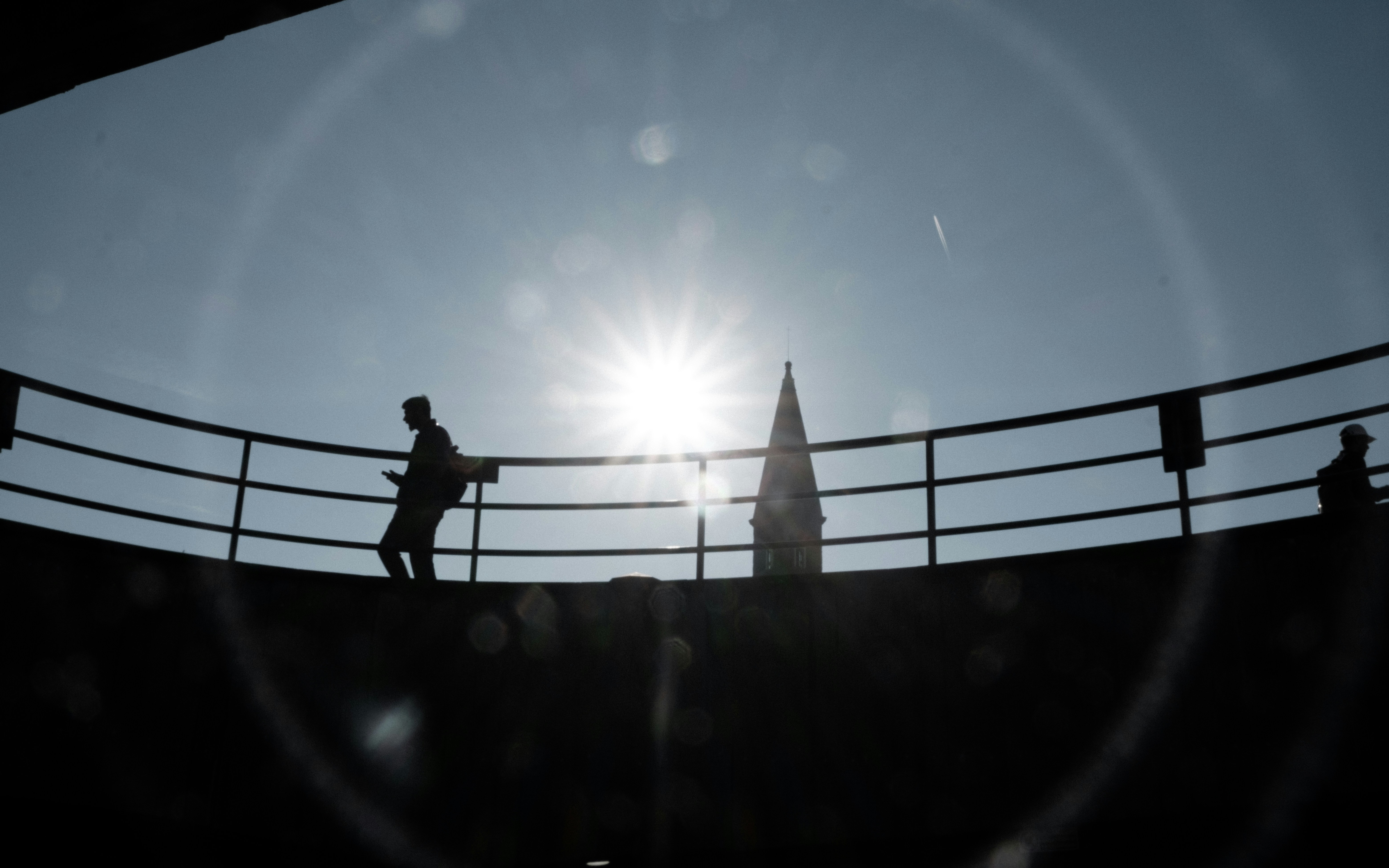 Silhouettes of people on a balcony against the sun.