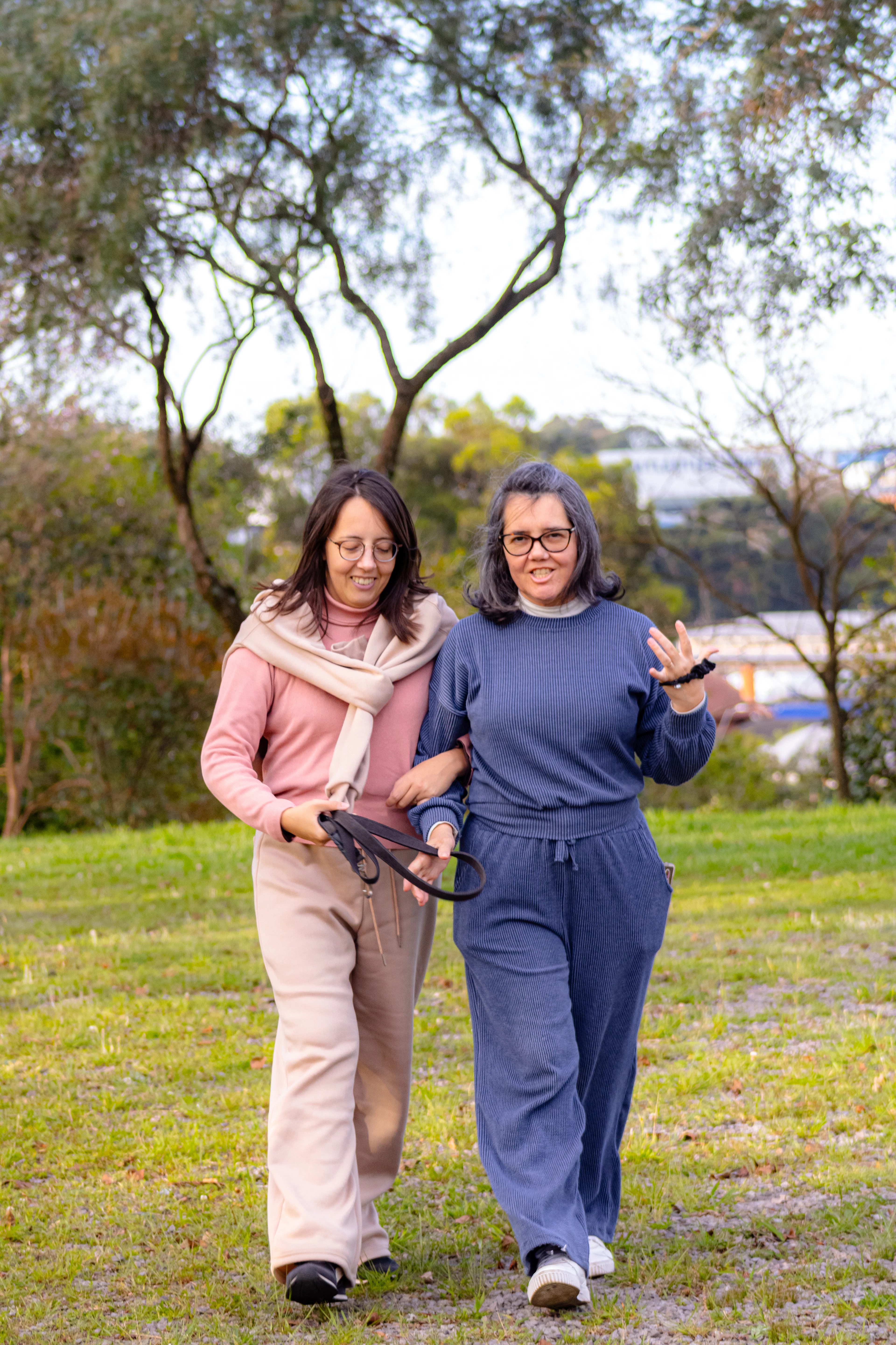 Two women laughing as they walk together in a park