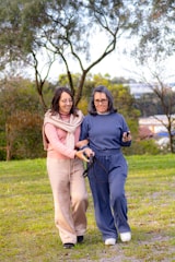 Two women walking together outdoors with arms linked.