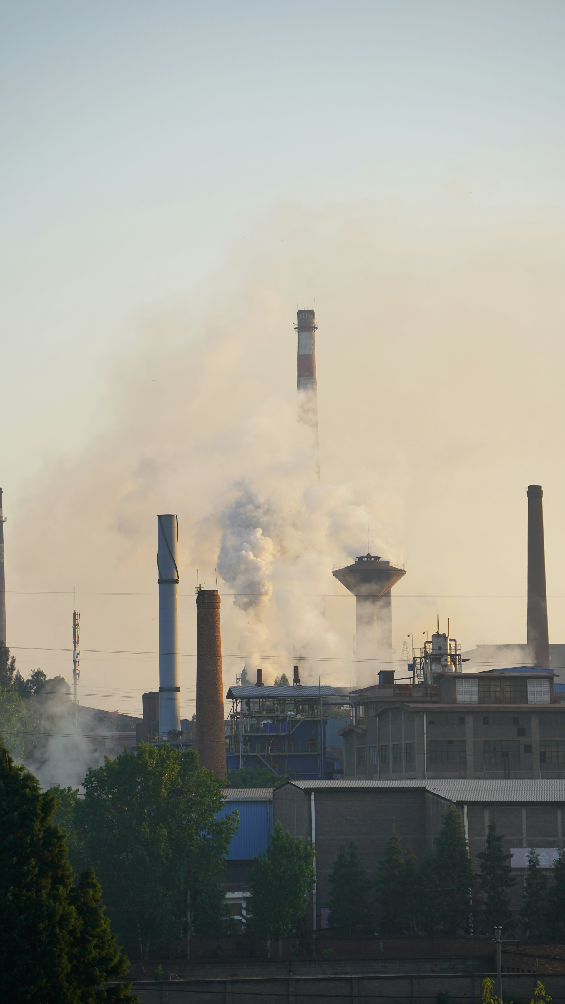 Industrial factory with smoke billowing from chimneys.